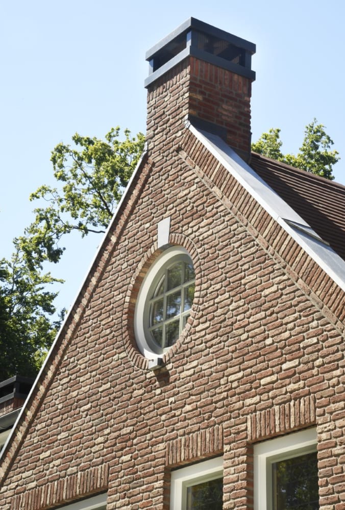 Rond raam hoog in een bakstenen topgevel