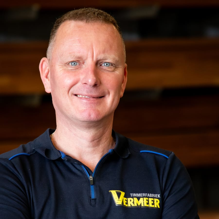Erwin, met de armen over elkaar voor de houtopslag