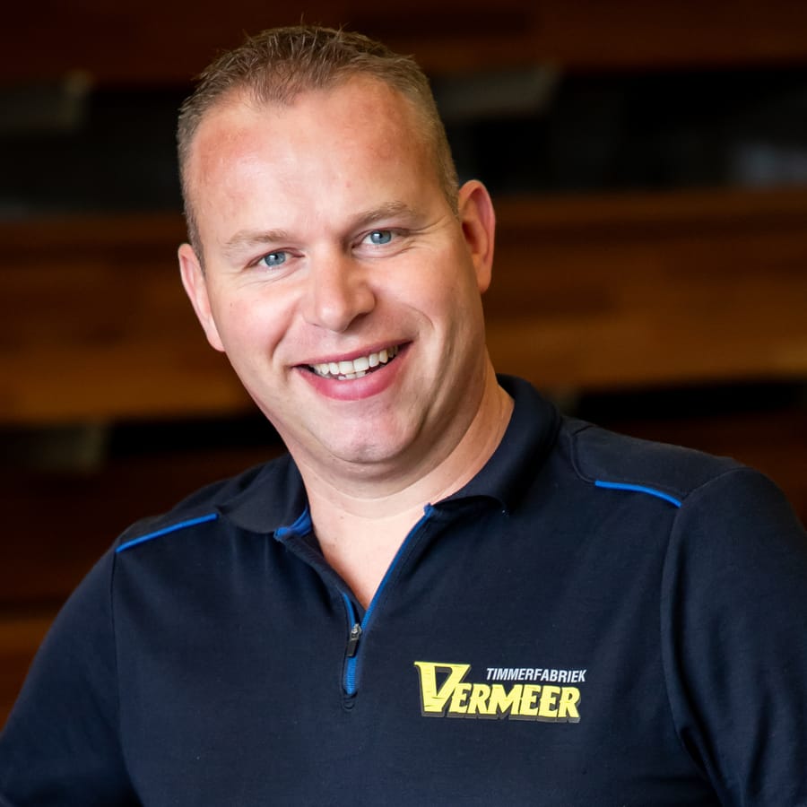 Gert, lachend met de handen in de zij in de fabriekshal