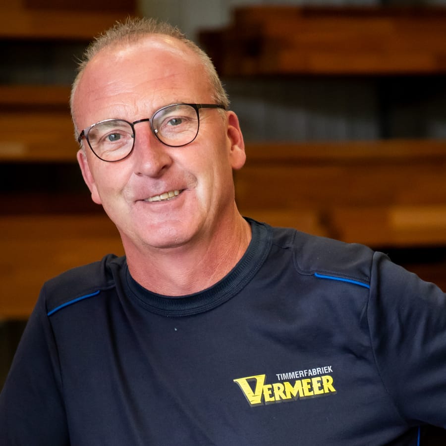 Helmert met bril, leunend op een stapel gestempeld hout