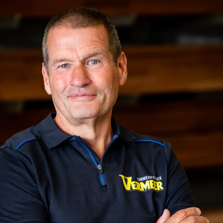 Huib, met de armen over elkaar voor de houtopslag